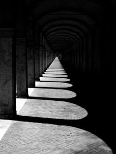 black and white photo of long walkways in an old building with light coming from the windows