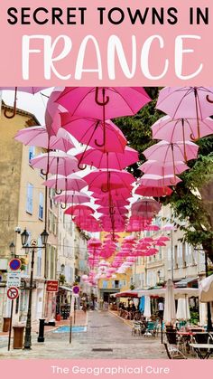 pink umbrellas hanging from the side of buildings with text overlay that reads secrets of the secret towns in france