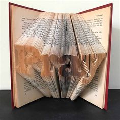 an open book with folded pages and the word love spelled out in it's center