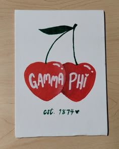 two cherries with the words gama phi on them are shown in white paper