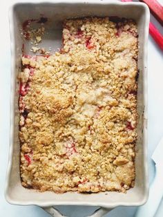 a square dish with crumbled topping and two red utensils next to it