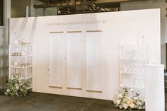 a white display with flowers and vases in front of it on a wooden floor