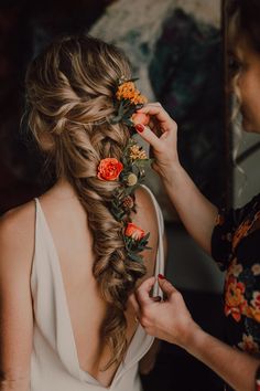 a woman is getting her hair done with flowers