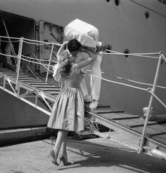 a woman in a dress standing on the steps of a ship with her back to the camera