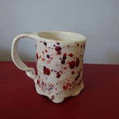 a white and red coffee cup sitting on top of a table