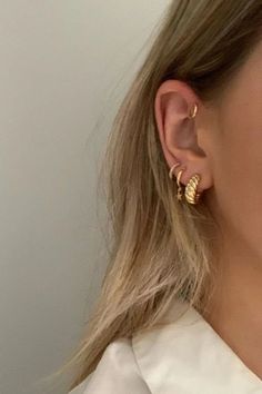 a close up of a person wearing gold earring and white shirt with long hair