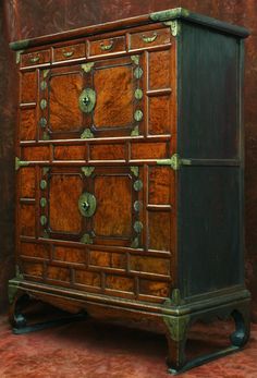 an old wooden dresser with metal handles and knobs on the front, against a brown background