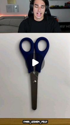 a man with headphones on is looking at a pair of scissors that have been cut in half