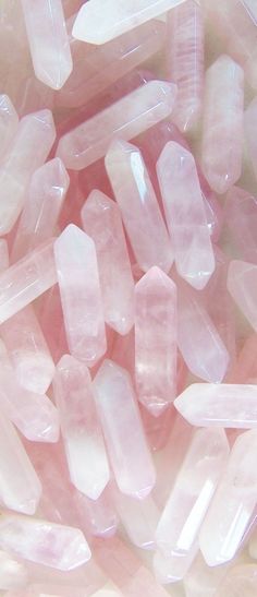 many pink crystals are scattered together in a pile on top of each other and one is white