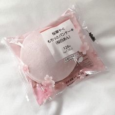 a pink bath ball in a package on a white sheet with japanese writing and cherry blossoms