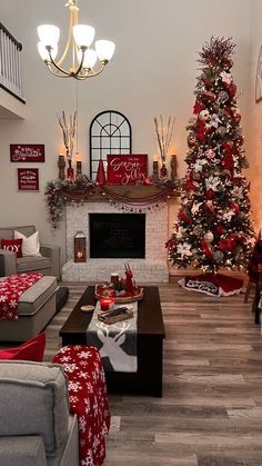 the living room is decorated for christmas with red and white decorations on the tree, couches, coffee table and fireplace