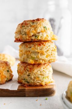 three crab cakes stacked on top of each other next to a plate of biscuits and a glass of milk