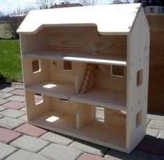 a wooden toy house sitting on top of a brick walkway