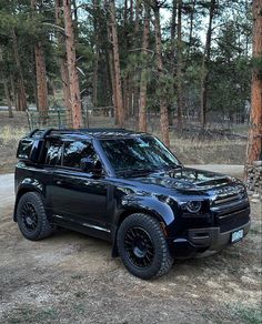 a black suv parked in front of some trees