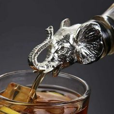 an elephant head is being poured into a glass filled with ice cubes and lemon wedges