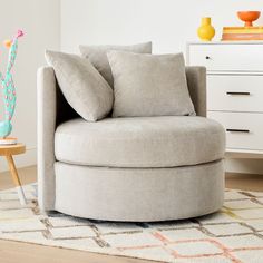 a living room with a round chair and pillows on the floor next to a white dresser