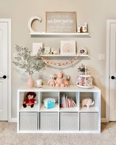 a white shelf filled with lots of toys next to a wall mounted clock and pictures