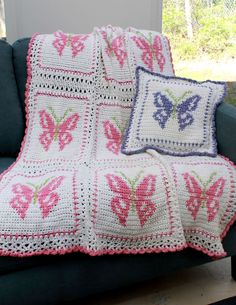 a crocheted butterfly afghan sits on a couch next to a pillow and throw