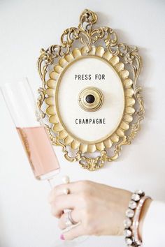 there is a champagne glass next to a clock on the wall that says press for champagne