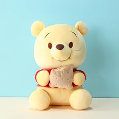 a teddy bear with a piece of cake in its mouth sitting against a blue background