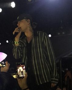 a man standing on top of a stage holding a microphone in his hand and singing