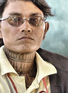 a man with tattoos on his neck wearing glasses