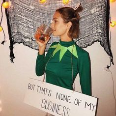 a woman holding a glass in front of her face while wearing a sign that says, but that's none of my business