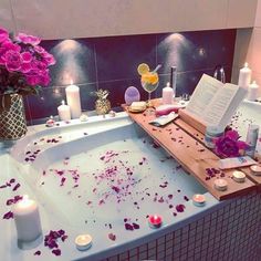 a bathtub filled with flowers and candles next to a book on top of it