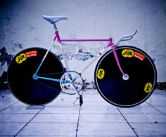 a pink and blue bike with wheels on it's front wheel is sitting in the middle of a tiled floor