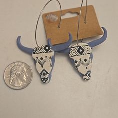 a pair of earrings that are sitting next to a penny