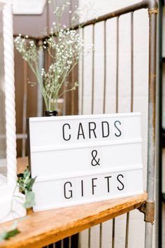 a sign that says cards and gifts on it next to a vase with baby's breath flowers