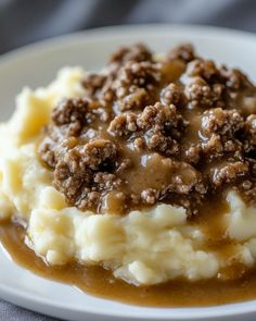 mashed potatoes topped with gravy and ground meat on a white dinner plate