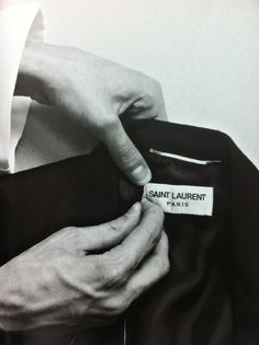 a black and white photo of someone's hand holding onto a jacket label that says saint laurent paris