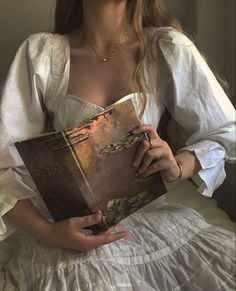 a woman sitting on a bed holding a book