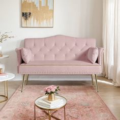 a pink couch sitting on top of a rug in a living room next to a table