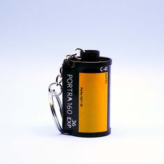 a yellow and black can with a keychain attached to it on a white background