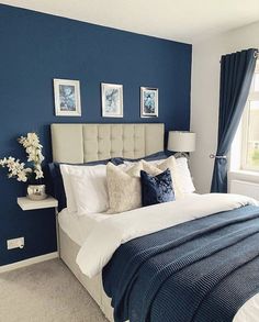 a bedroom with blue walls, white bedding and pictures on the wall above it