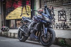 the motorcycle is parked on the side of the street next to some graffiti covered buildings