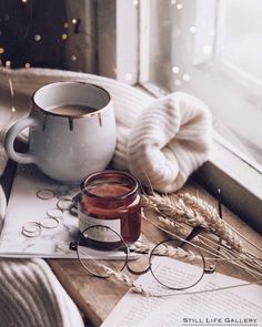 a cup of coffee, eyeglasses and some books on a window sill