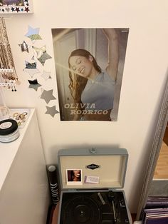 an old record player sitting on top of a wooden table next to a wall with pictures