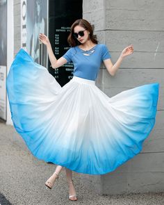 "Elevate your style with our white and blue gradient high-waisted chiffon swing skirt. The ombre color transition from white to blue adds a touch of whimsy and charm. The high-waisted design cinches your waist and elongates your legs for a flattering silhouette. Crafted from lightweight chiffon fabric, this skirt is comfortable and allows for easy movement. The swing style creates a playful and romantic look, perfect for summer events and beach outings. Embrace the beauty of the ombre trend with Ombre Fabric Fashion, White And Blue Skirt Outfit, White Flowy Ruffled Maxi Skirt, Flowy White Skirt For Spring, White Pleated Midi Dress, White Flowy Ruffled Skirt Bottoms, White Flowy Gathered Maxi Skirt, White Flowy Ruffled Skirt, White Flowy Maxi Skirt With Gathered Details