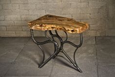 a wooden table sitting on top of a cement floor next to a brick wall with an iron frame