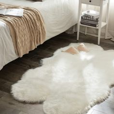 a white sheepskin rug on the floor next to a bed with a night stand