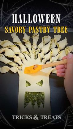 halloween savory pastry tree with wooden spatula in front of it and hand holding spoon