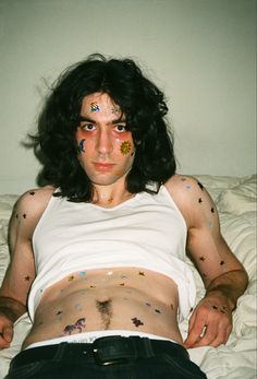 a man laying on top of a bed covered in tattoos