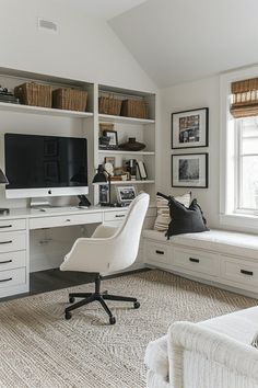 a home office with white furniture and lots of storage space on the wall above it