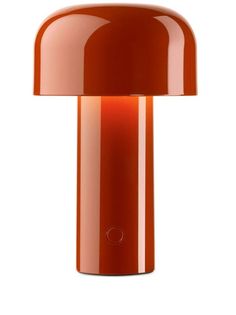 an orange table lamp on a white surface with a light bulb in the shape of a mushroom