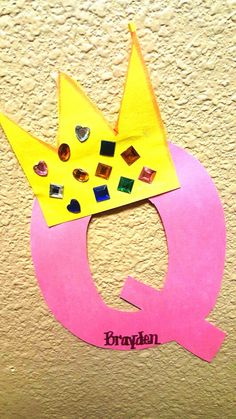 a paper crown on top of a pink letter q