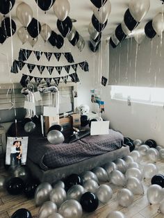 a room filled with balloons and black and white decorations hanging from the ceiling over a bed