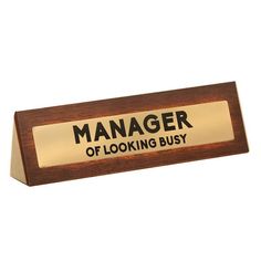 a wooden sign with the words manager of looking busy on it's front side